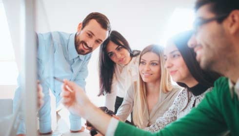 Photo d'une jeune équipe multiethnique travaillant ensemble dans un bureau moderne ; ils se consultent au sujet d'un problème tout en restant assis