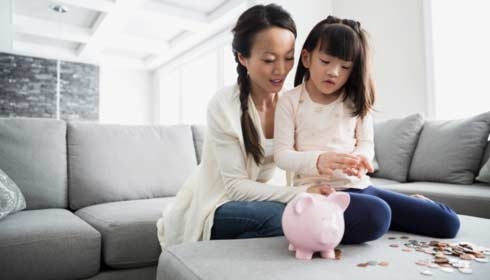 Une mère et sa fille qui comptent les pièces d'une tirelire