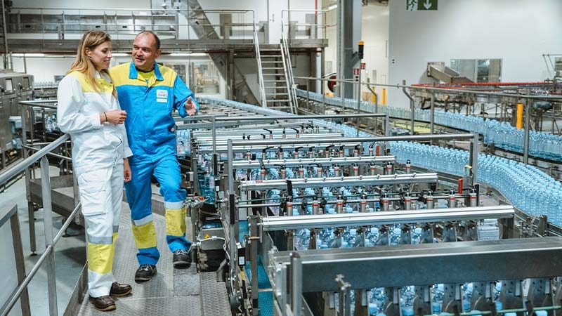 A person and person walking in a factory