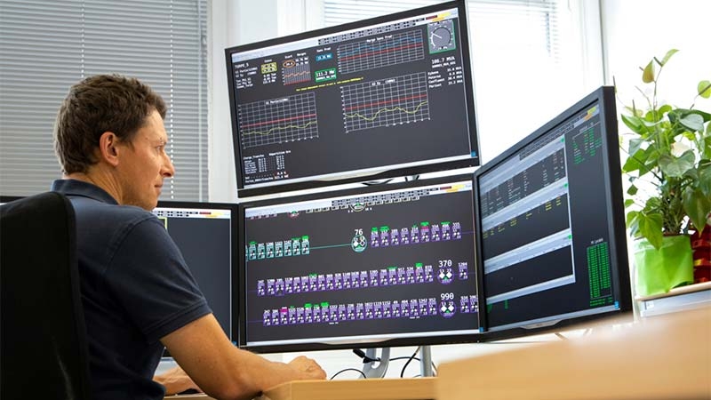 A person sitting at a desk looking at multiple monitors