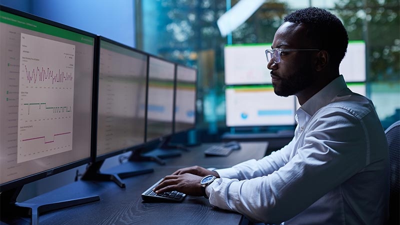 A person sitting at a desk with several computer screens