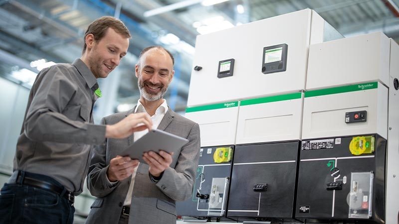 Men standing next to each other looking at a tablet