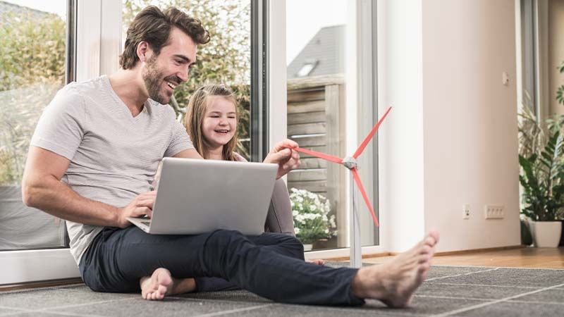 A person and a child sitting on the floor with a windmill