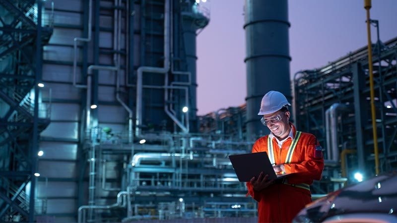 A person in hardhat and hard hat holding a computer