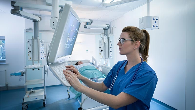 A person in a blue scrubs using a computer