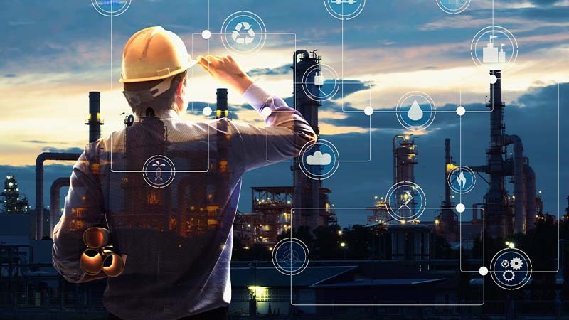 A person in a hard hat looking at a factory