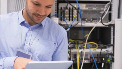 Man in data center with tablet, data center management, data center operations.