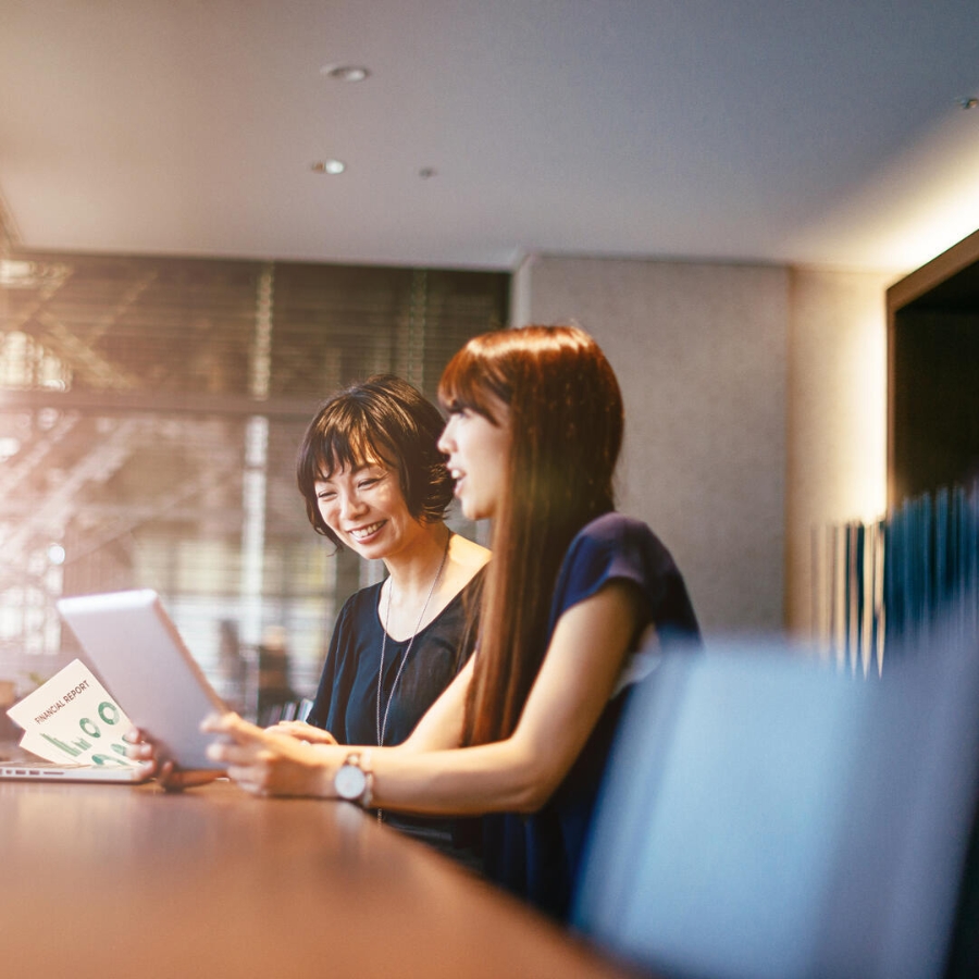 Two young Japanese business women discussing with each other