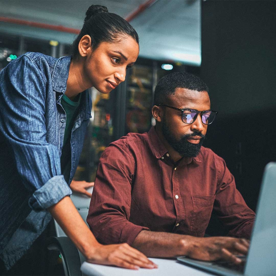 A person standing next to a person using a computer