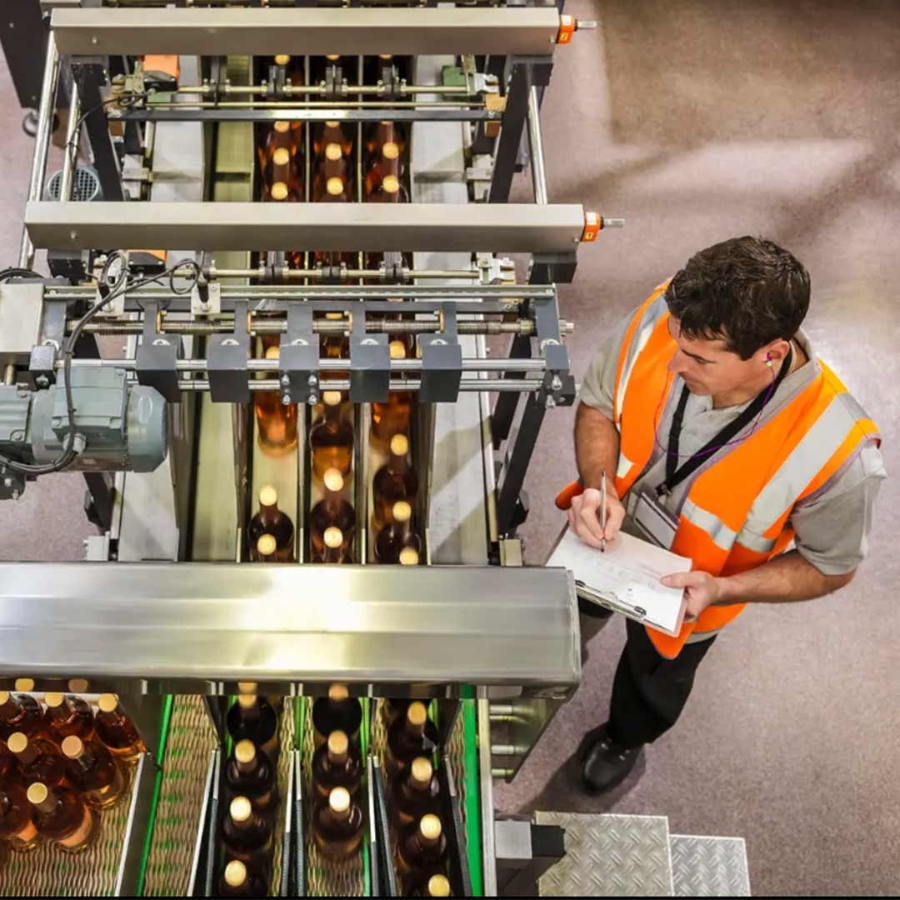 A person in orange vest standing next to a conveyor belt