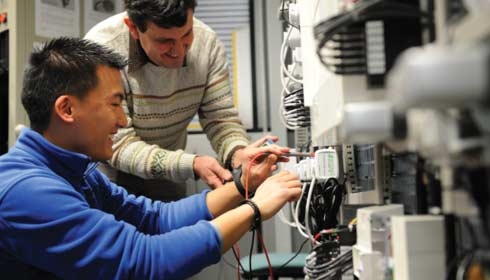 Collaborateur montrant à un collègue comment se servir d'un multimètre, gestion des actifs, rendement énergétique