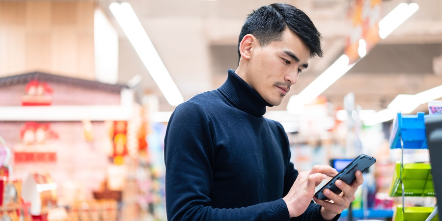 man using cell phone at checkout counter in the supermarket