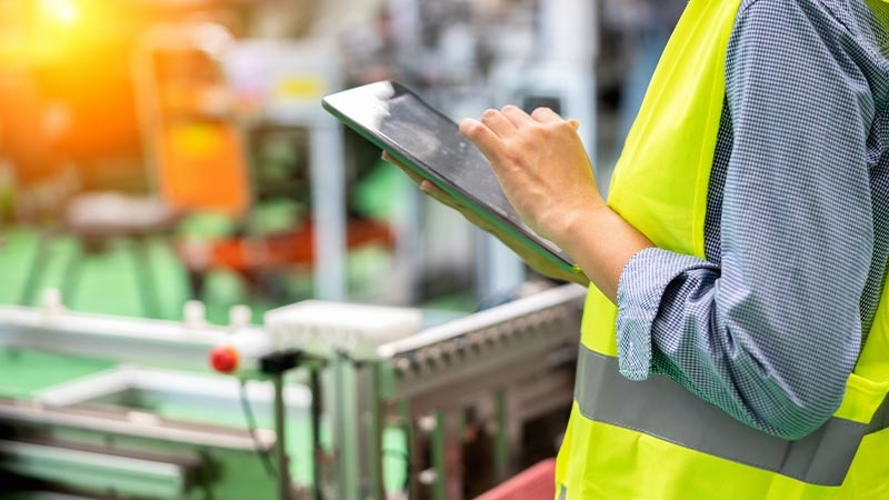 A person in a yellow vest using a tablet