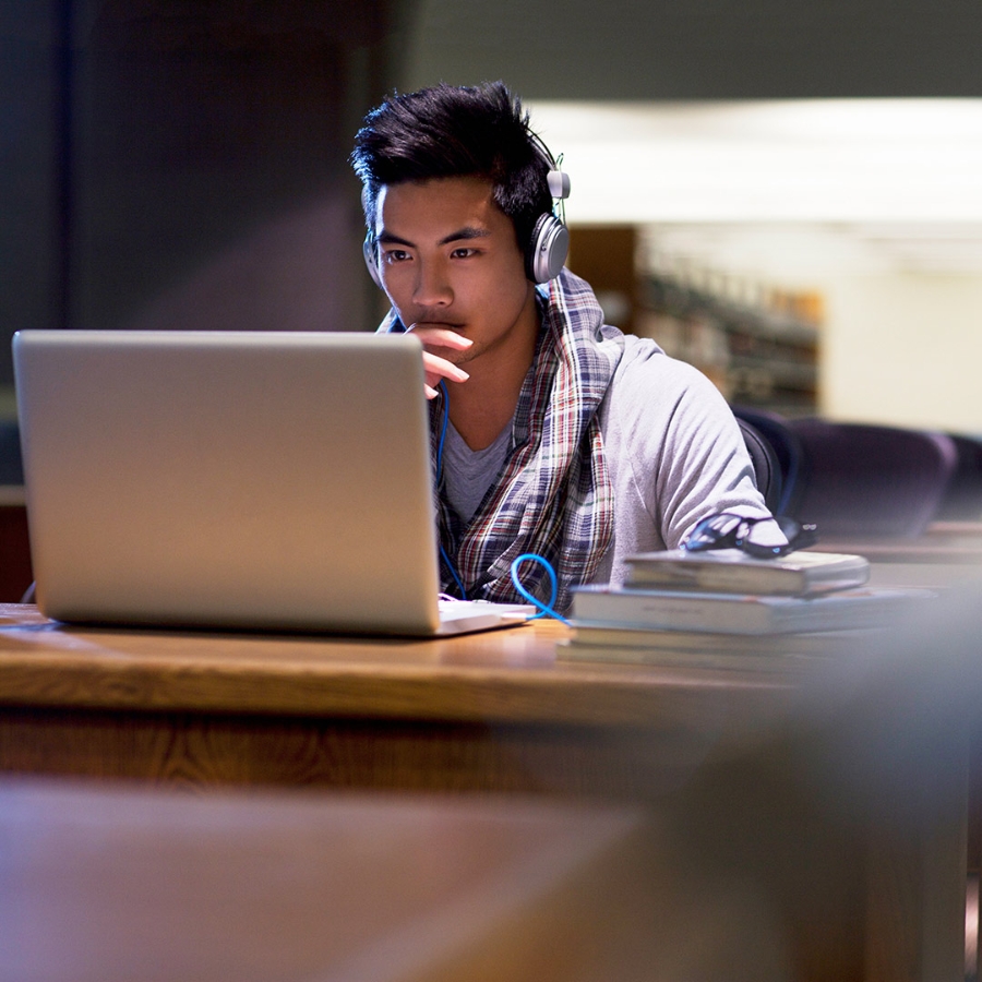 young man wearing headphones working on a laptop