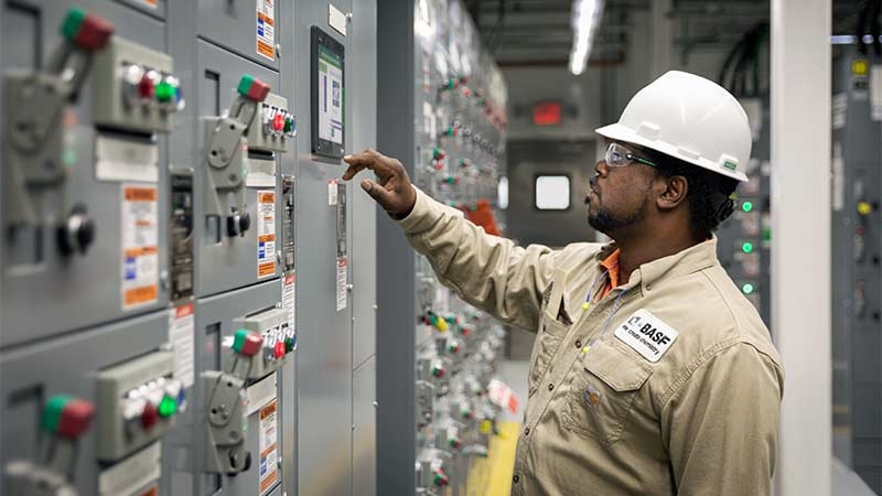 A person wearing a hard hat and working on a machine