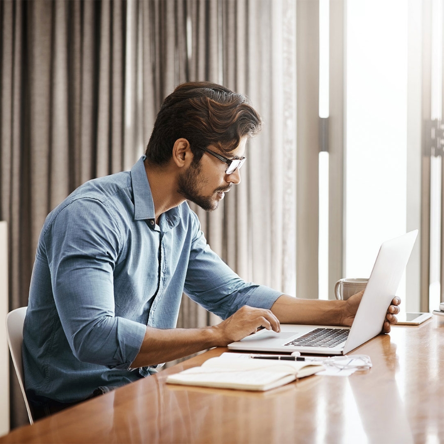 man sitting at his desk working on a laptop