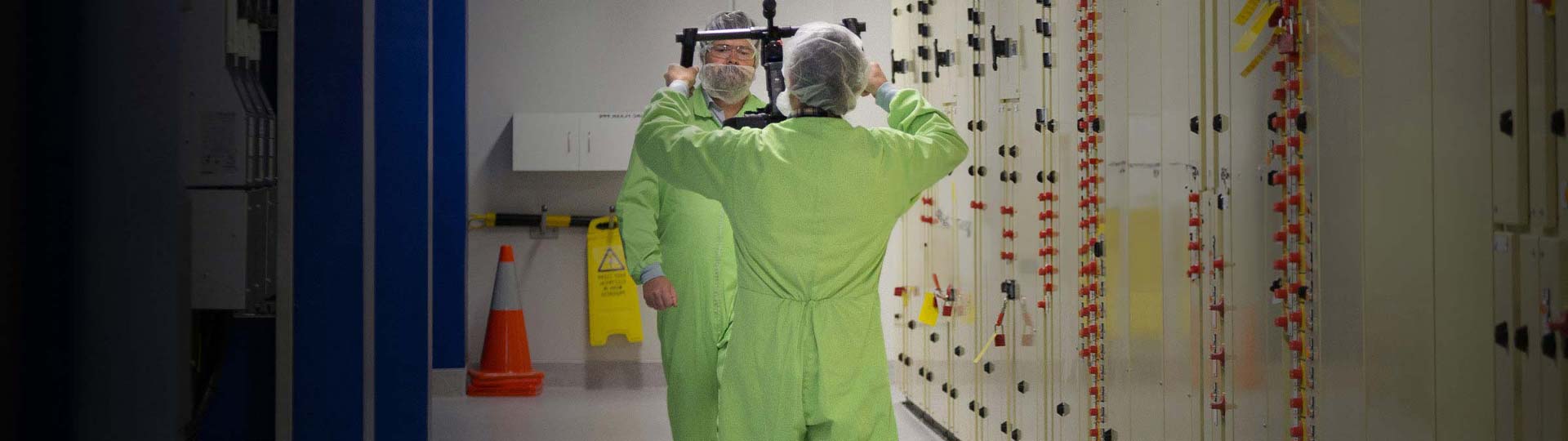 A person in green jumpsuits standing in a room with a mirror