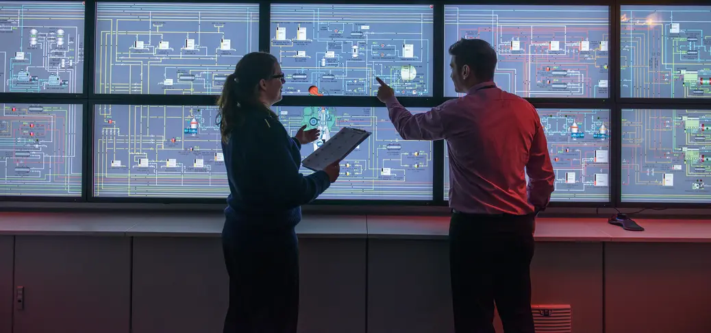 Two employees analyzing data in the control room.