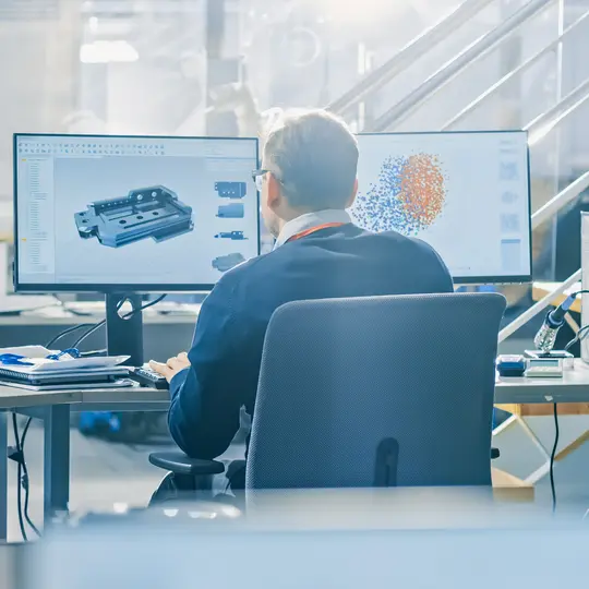 Back view of Industrial engineer working on desktop computer in bright office