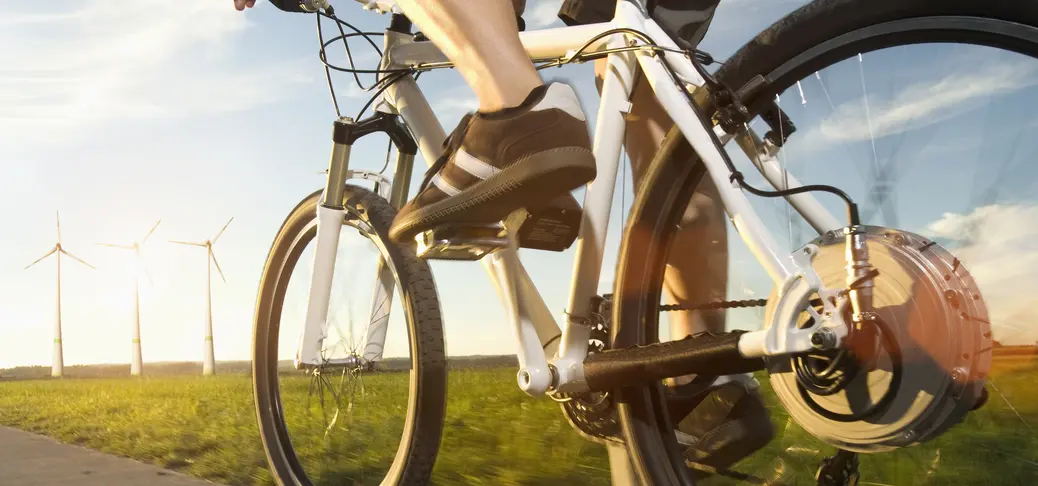 Man bicycling toward wind turbines.