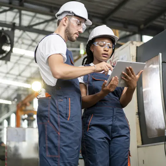 Technician engineer have to consult with colleagues while operating CNC milling machine in manufacturing workshop