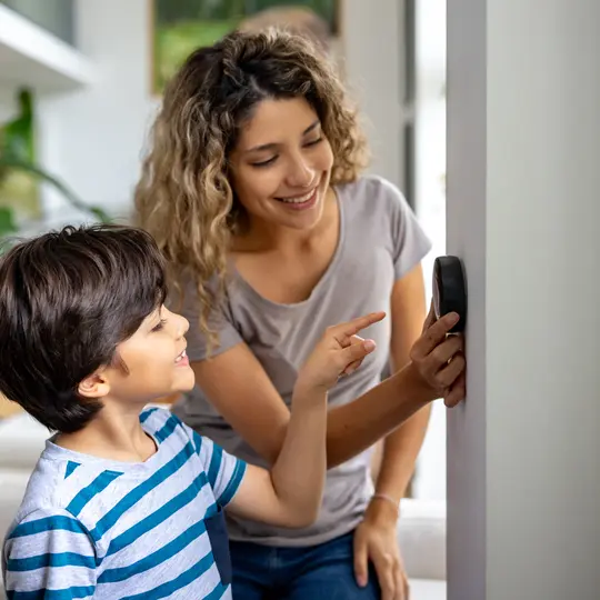 Mother and son at home using a smart thermostat