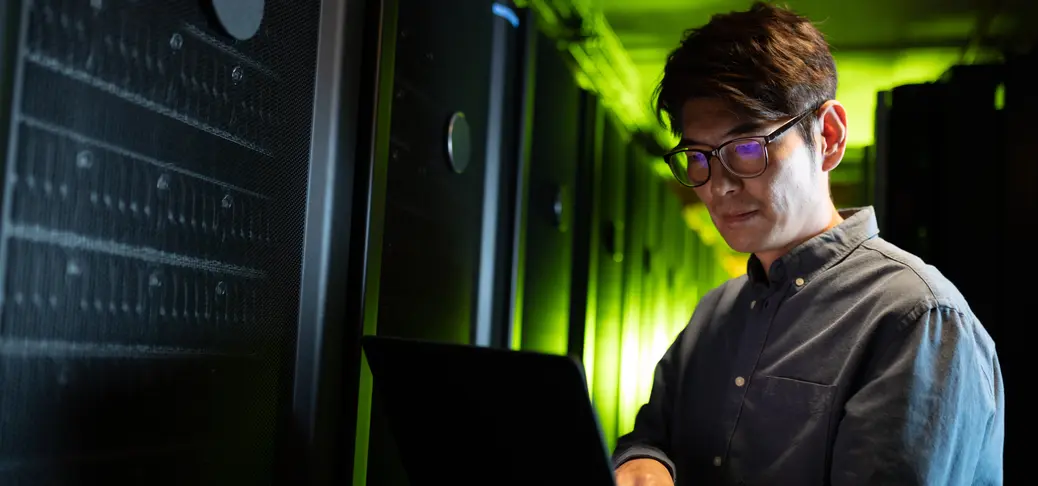 Engineer using laptop in computer server room. database server management and maintenance concept