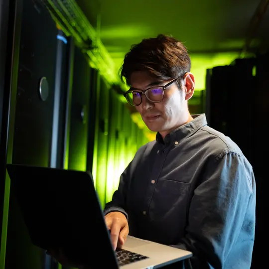 Engineer using laptop in computer server room. database server management and maintenance concept