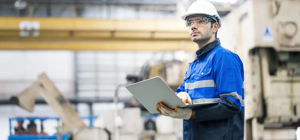 Industrial system integrators in white hats look at data during maintenance.