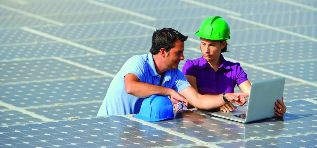  Professional electric engineers survey and inspect solar panels installation on the factory metal sheet rooftop.