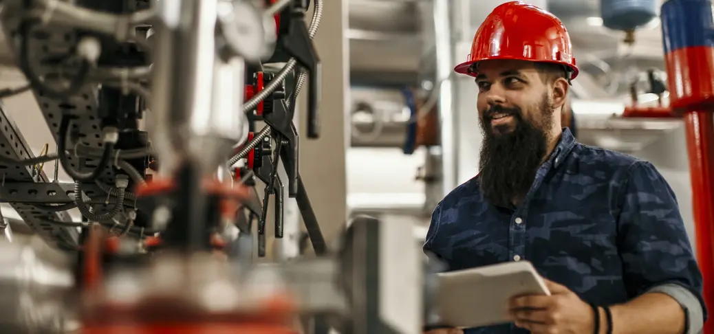 Factory engineer in work uniform using laptop computer with software.