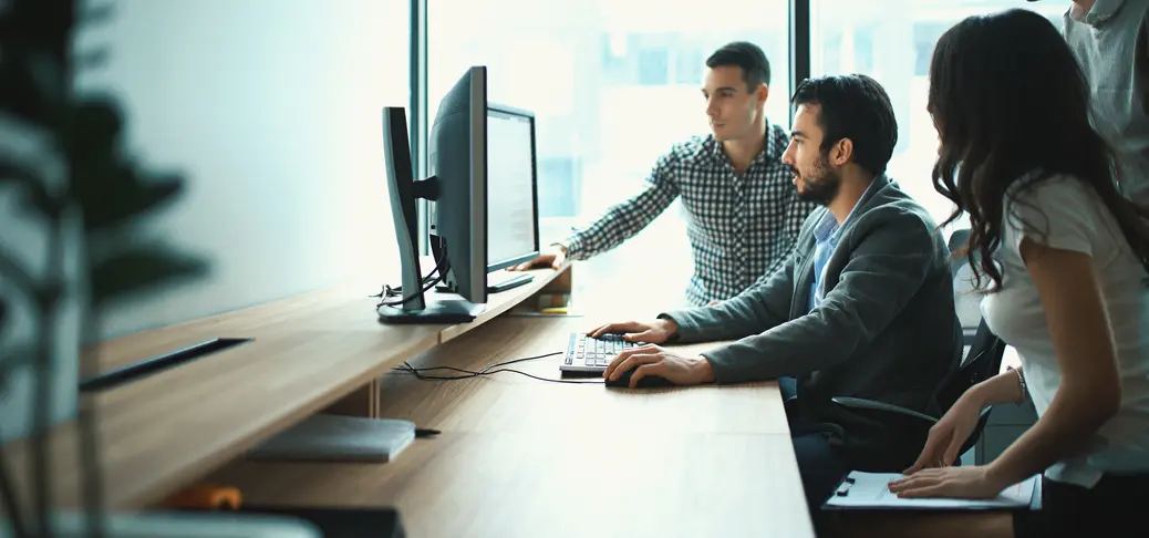 Closeup side view of group of young IT experts completing a task, a part of their daily routine at IT company