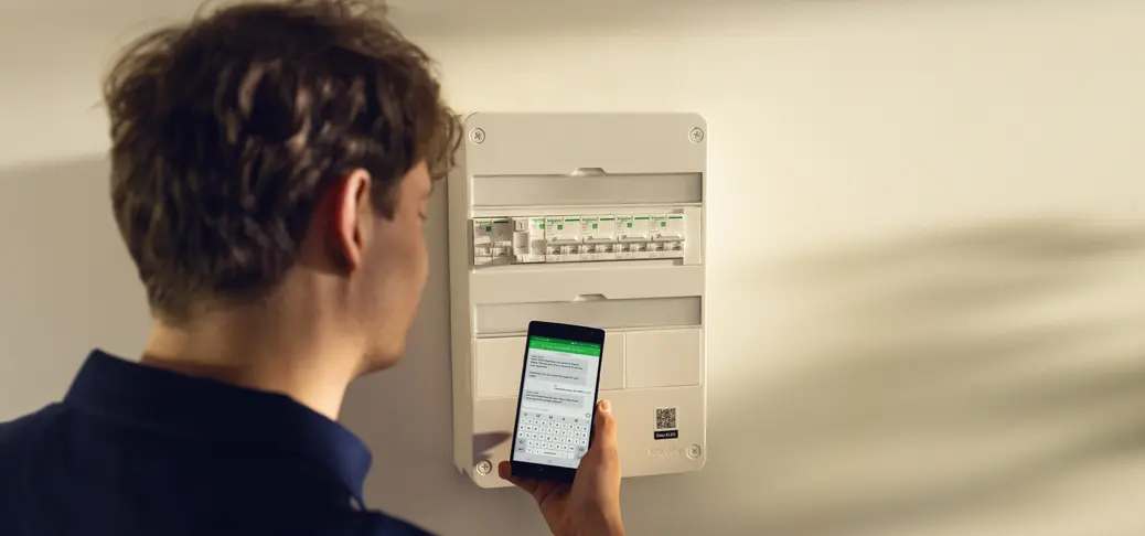 Contractor using a smartphone near a circuit breaker.