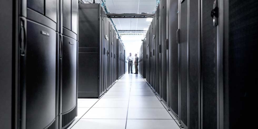 Deux hommes debout dans une rangée de datacenters, gestion des datacenters, entreprise informatique.