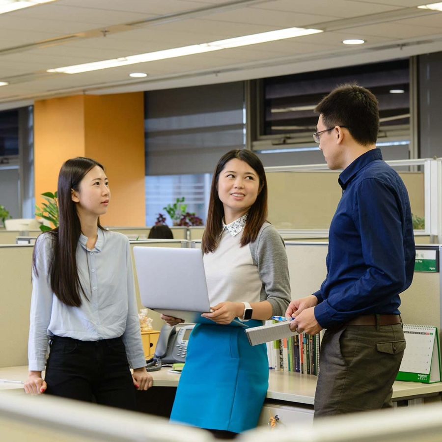 A group of three employees discussing in office while standing