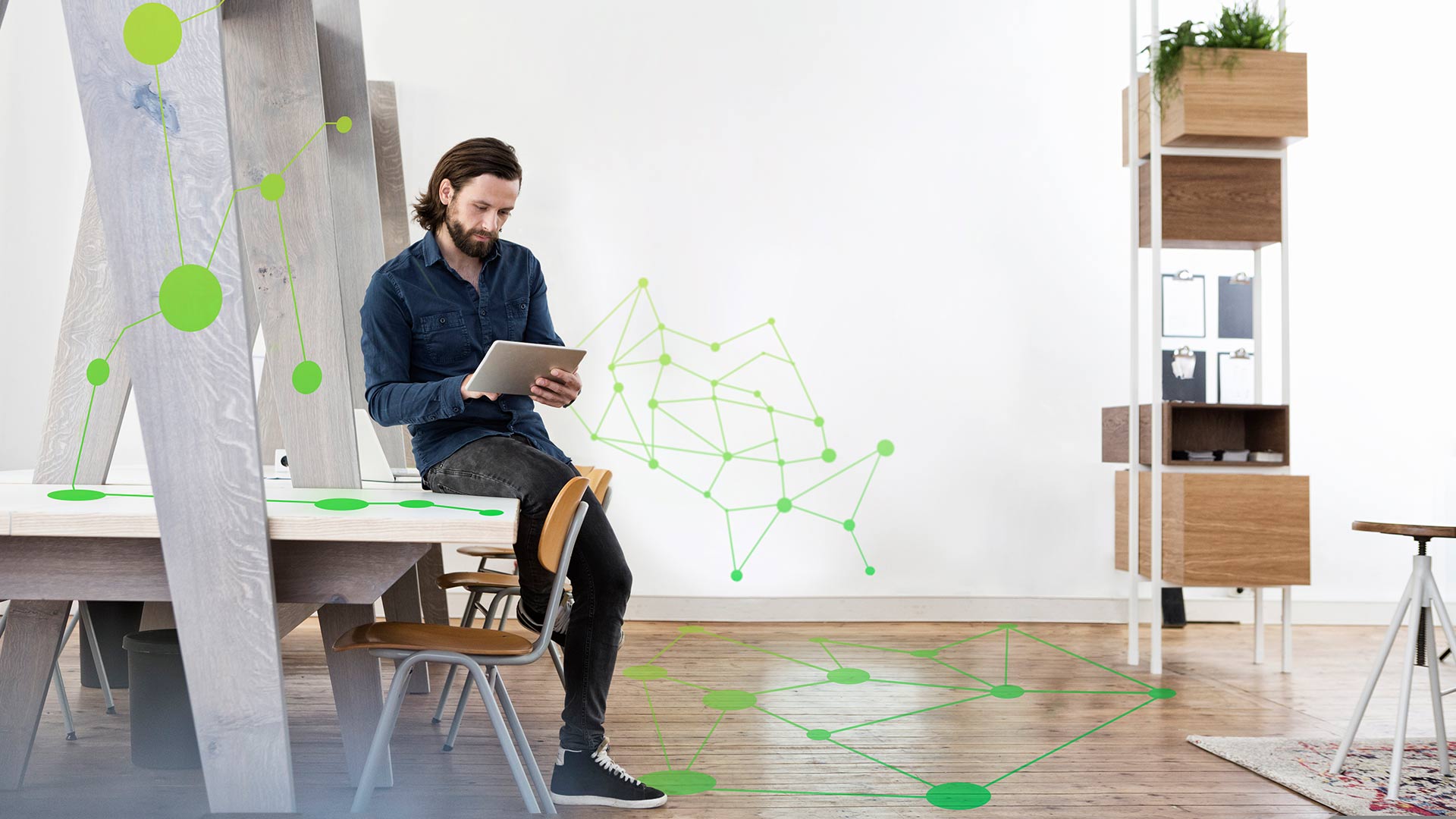 man using a digital tablet while sitting on an office table