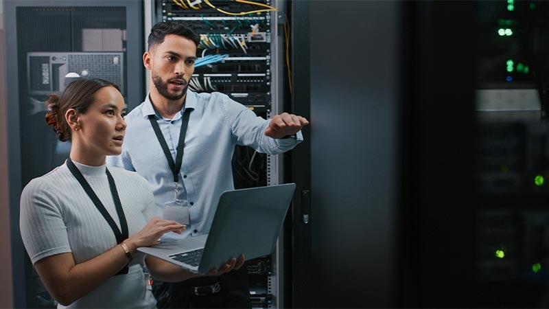 A person and person standing in a room with a computer