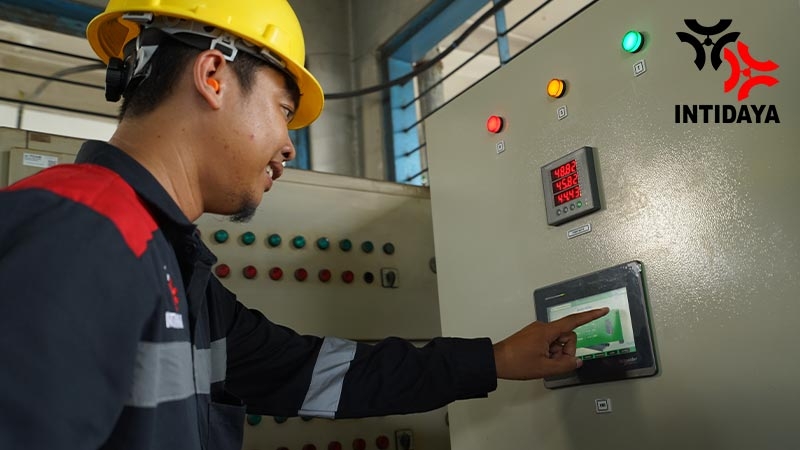 A person wearing a hard hat pointing at a touch screen