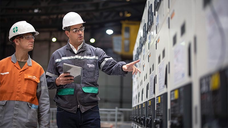 A person wearing a hard hat pointing at a tablet