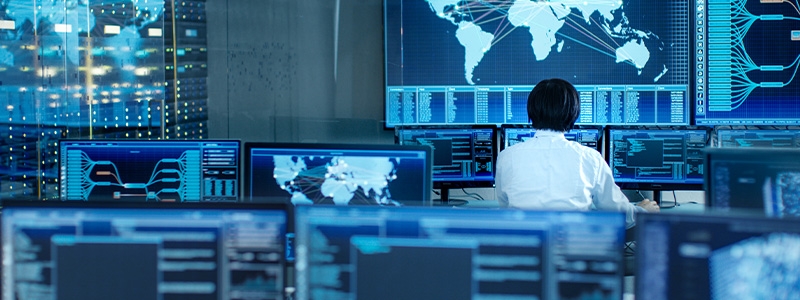 In the System Control Room Operator Sits at His Workstation with Multiple Displays Showing Graphics and Logistics Information.