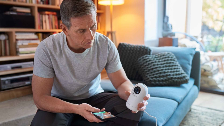man holding a home security camera and a mobile at home