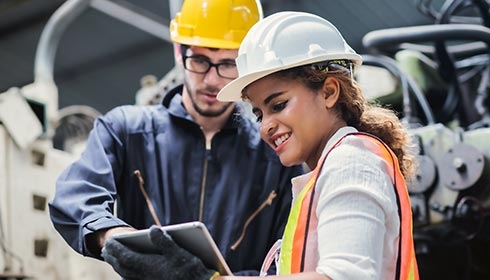 Two engineers wearing safety hats discussing at site