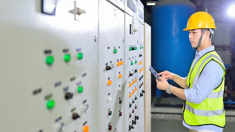 Engineer at an electricity substation holding a digital tablet