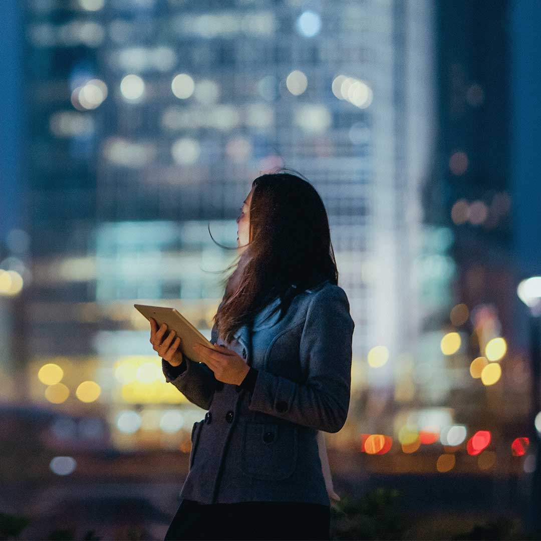 A person holding a tablet in front of a city