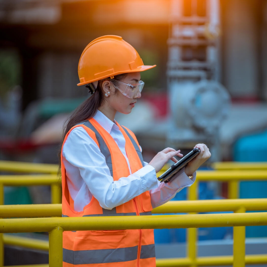 A female worker wearing a cap searching something on a tablet.