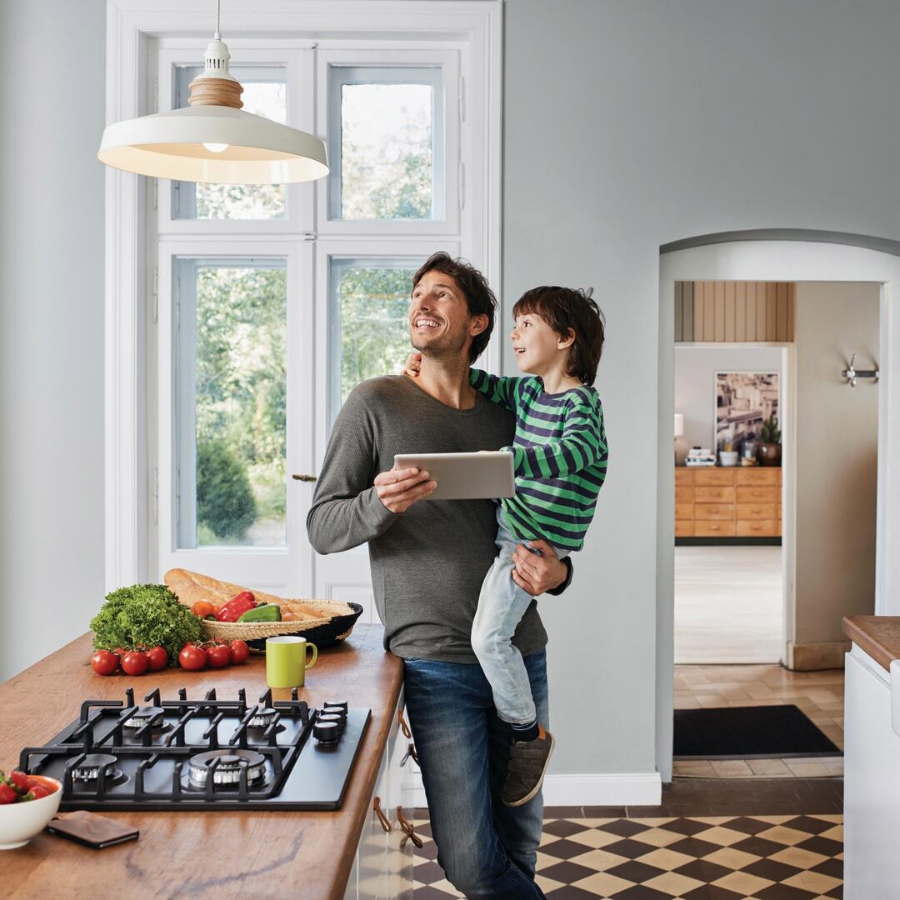 father with son controlling kitchen lamp via tablet computer