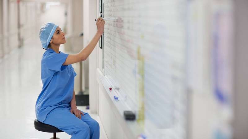 A nurse writing on a whiteboard