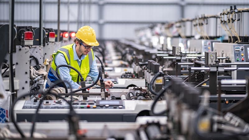 A person in a yellow helmet working in a factory