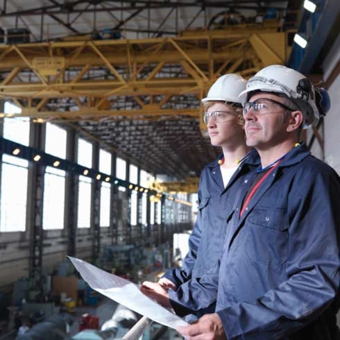 Engineers above turbine hall reviewing plans, industrial automation, machine control, sustainability reporting.