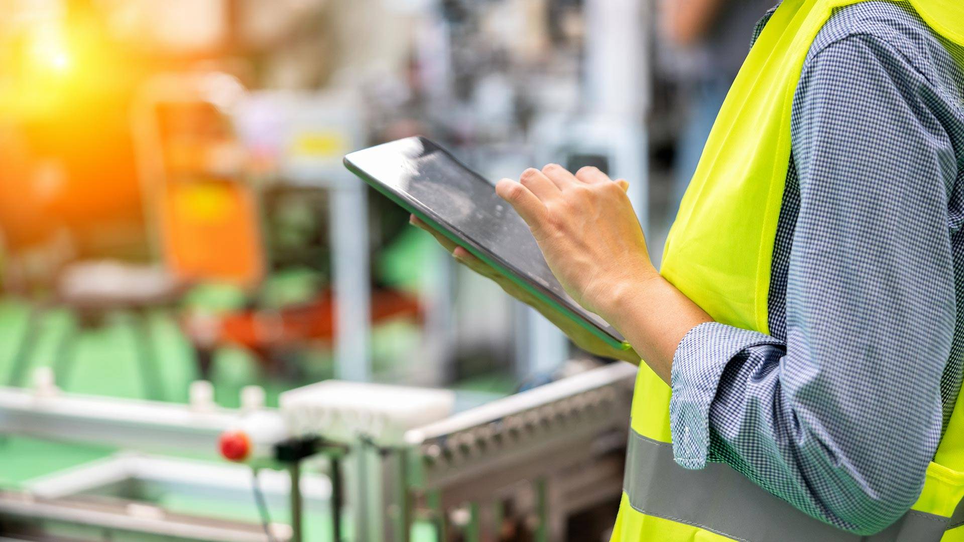 A person in a yellow vest using a tablet